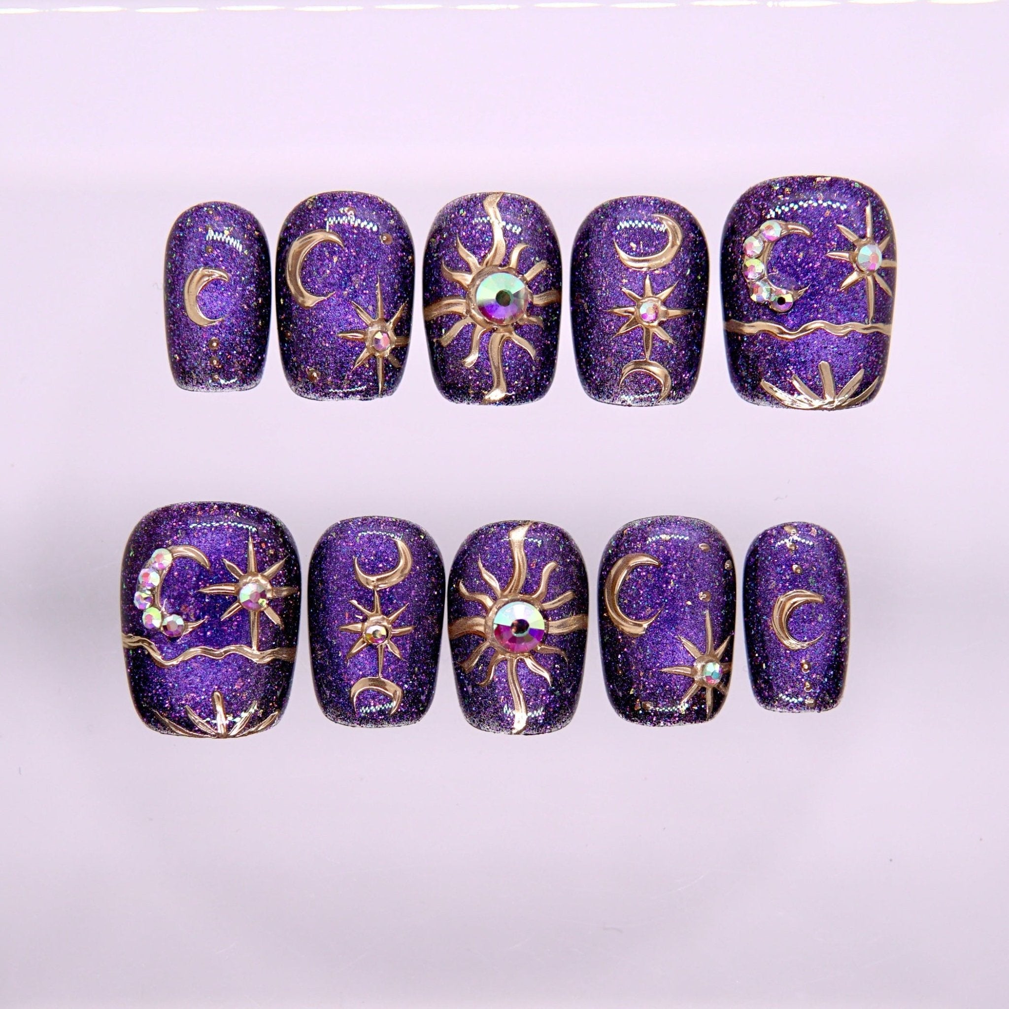 Begin with Wonder press-on nails set featuring deep purple tones with celestial star and moon details and soft shimmer