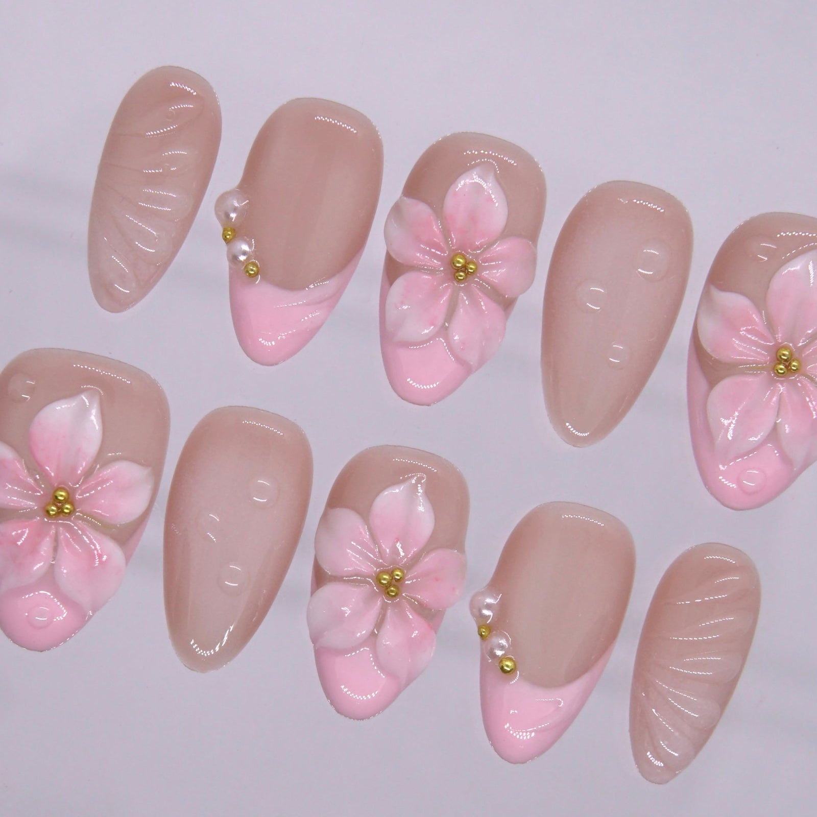 Close up of sculpted pink 3D flower nail with gold bead detail and glossy finish.