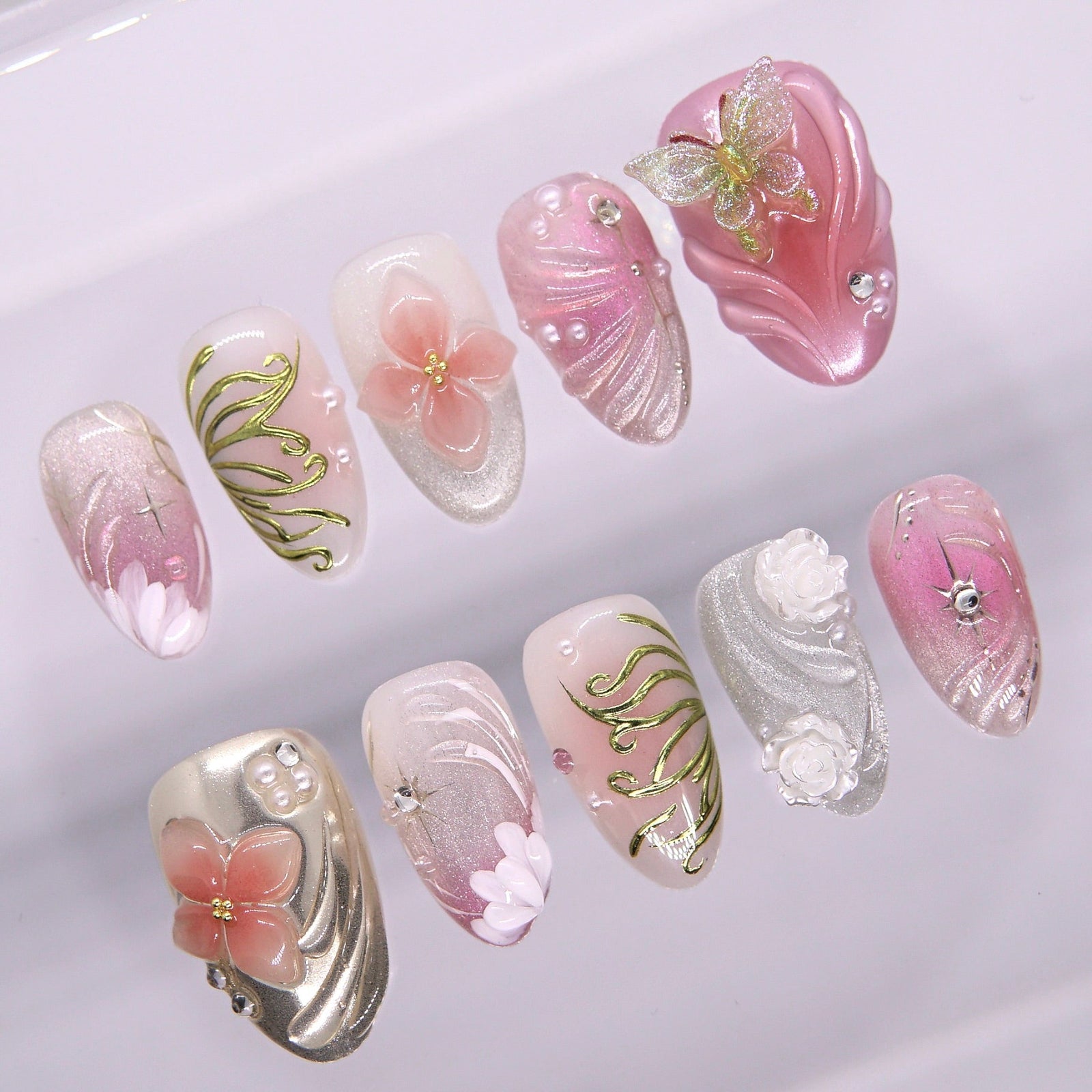 Pink fantasy press-on nails with sculpted 3D florals, butterflies, and golden vines from the Water · Flow collection by Nailsium.