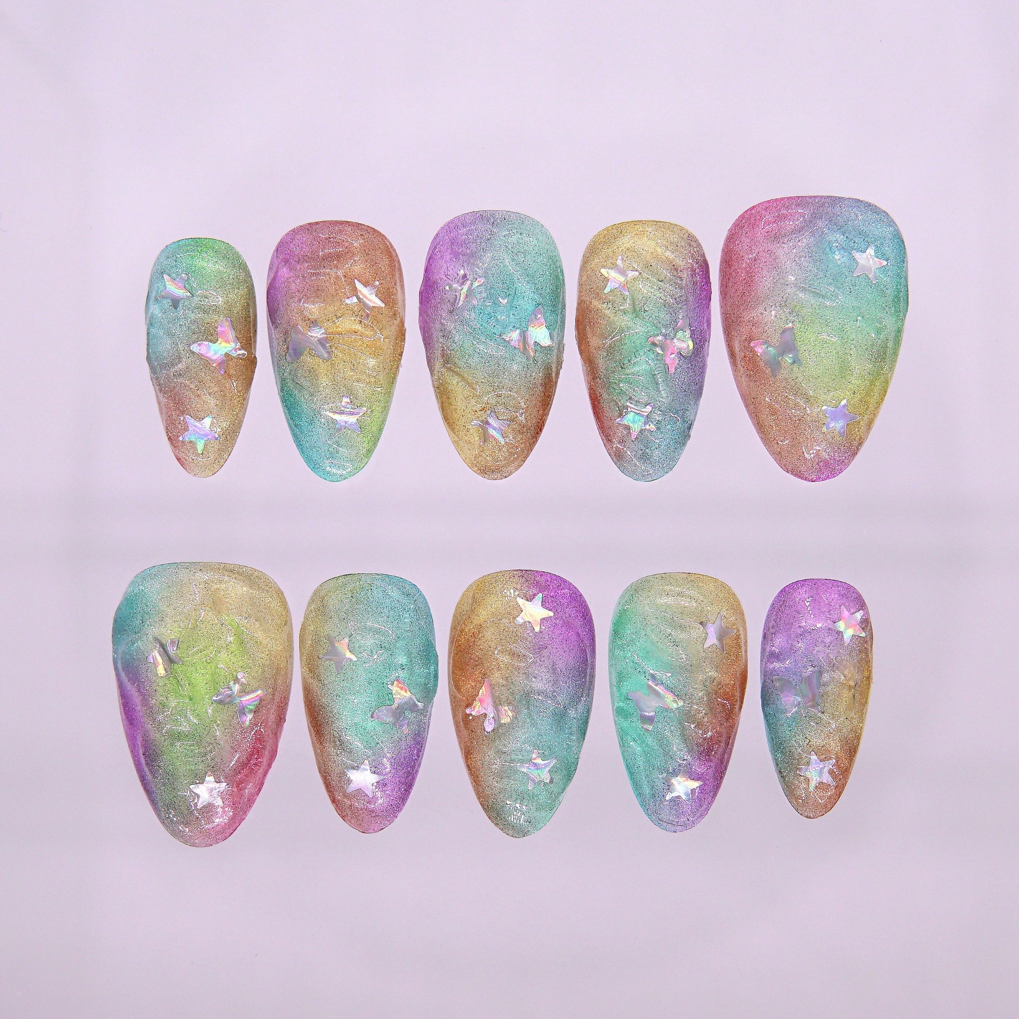 Top view of Fairy Shells press-on nails with iridescent rainbow shimmer and holographic star sequins.
