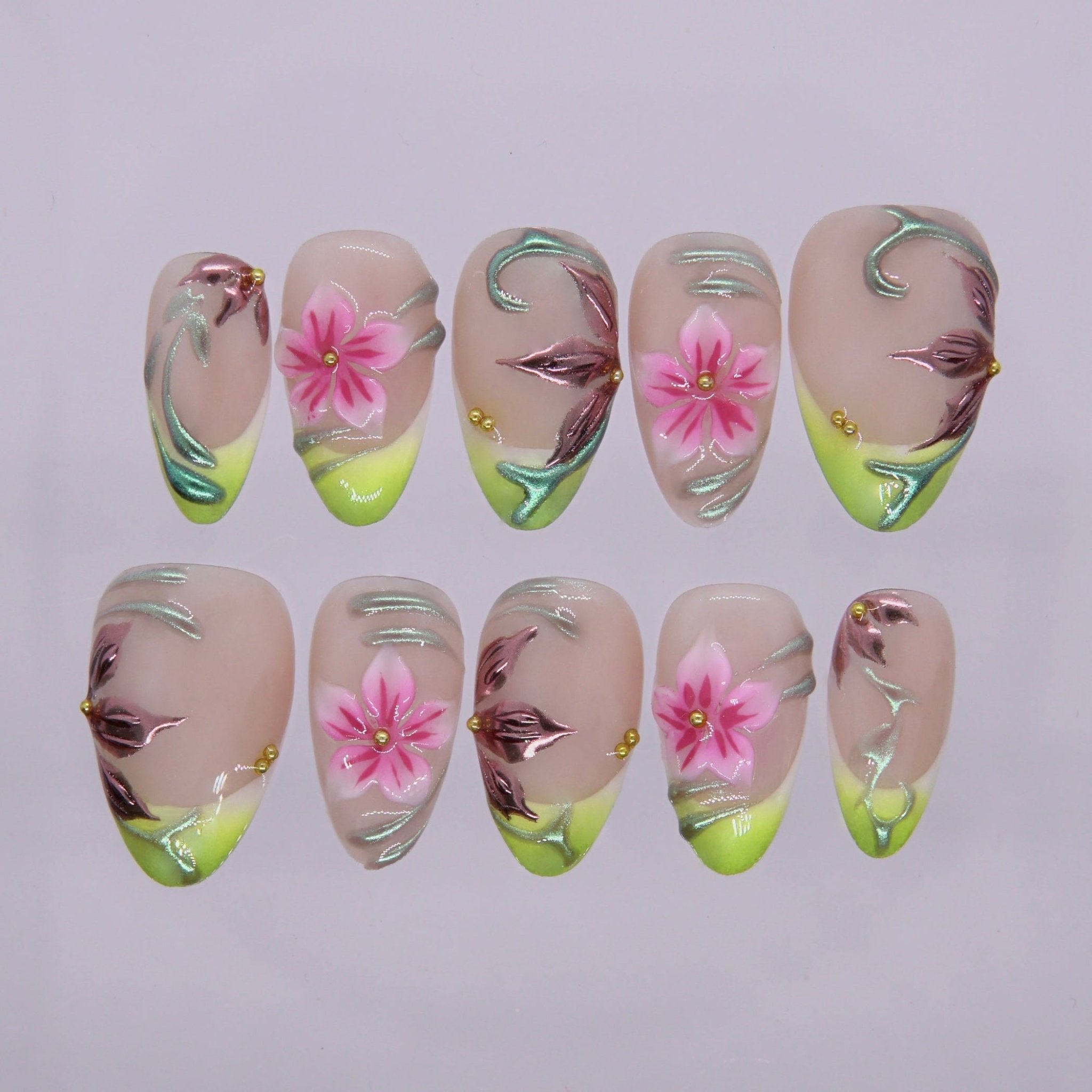 Handmade almond press on nails with sheer nude base, lime green French tips, pink floral accents, and metallic swirl details