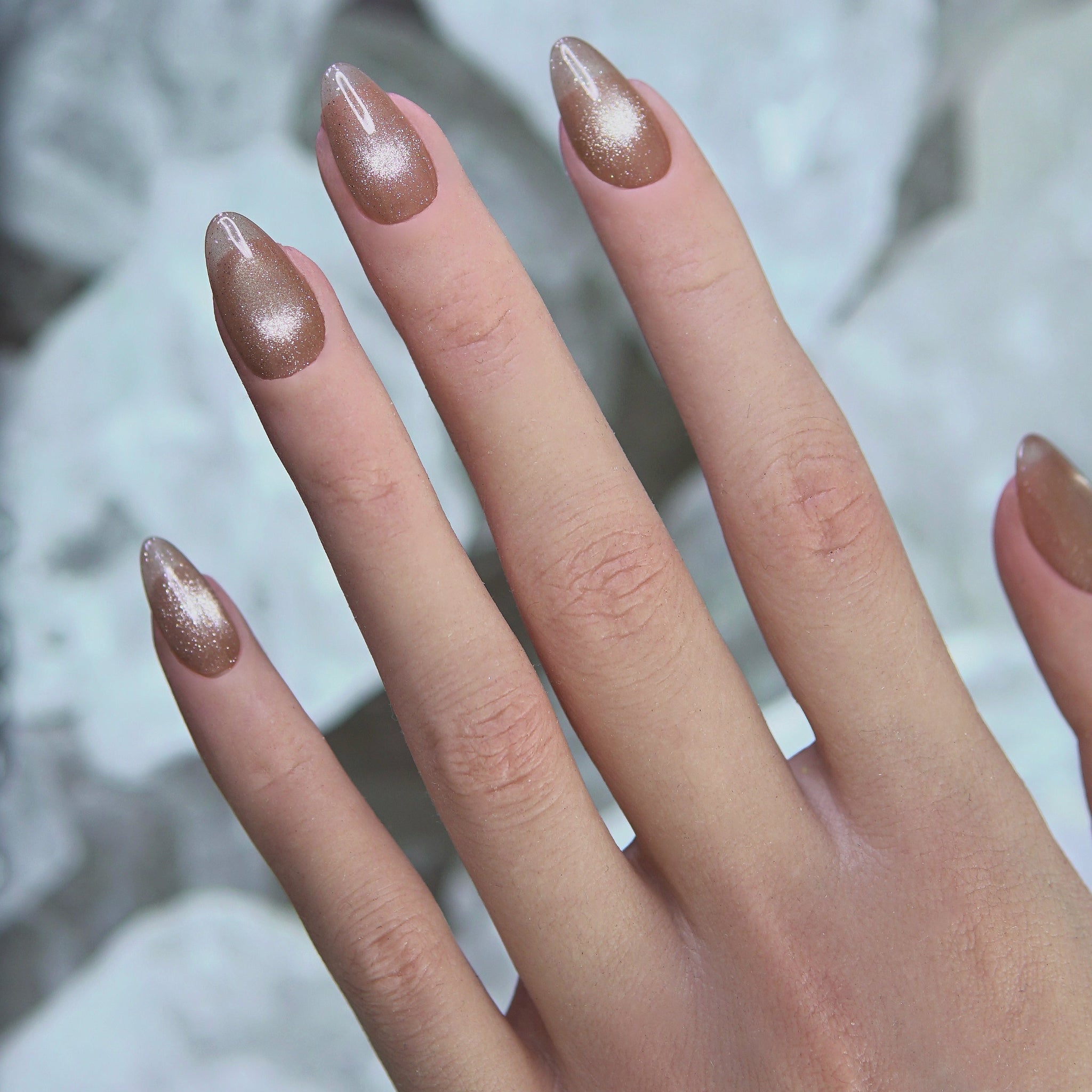 First Light champagne cat eye nails worn on hand in soft daylight – gentle and glowing