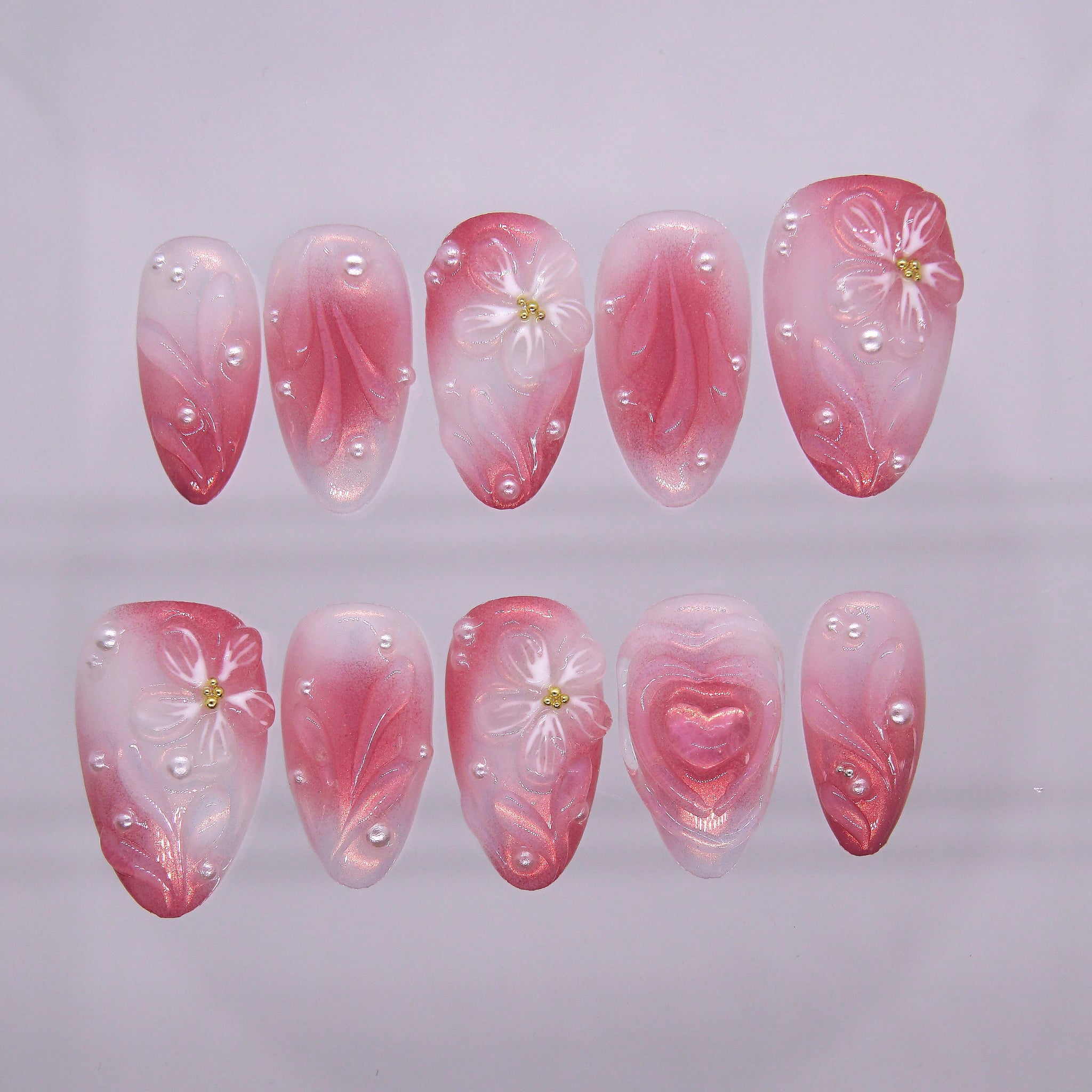 Detailed view of 3D heart centerpiece with shimmer finish on soft girl press-on nails.