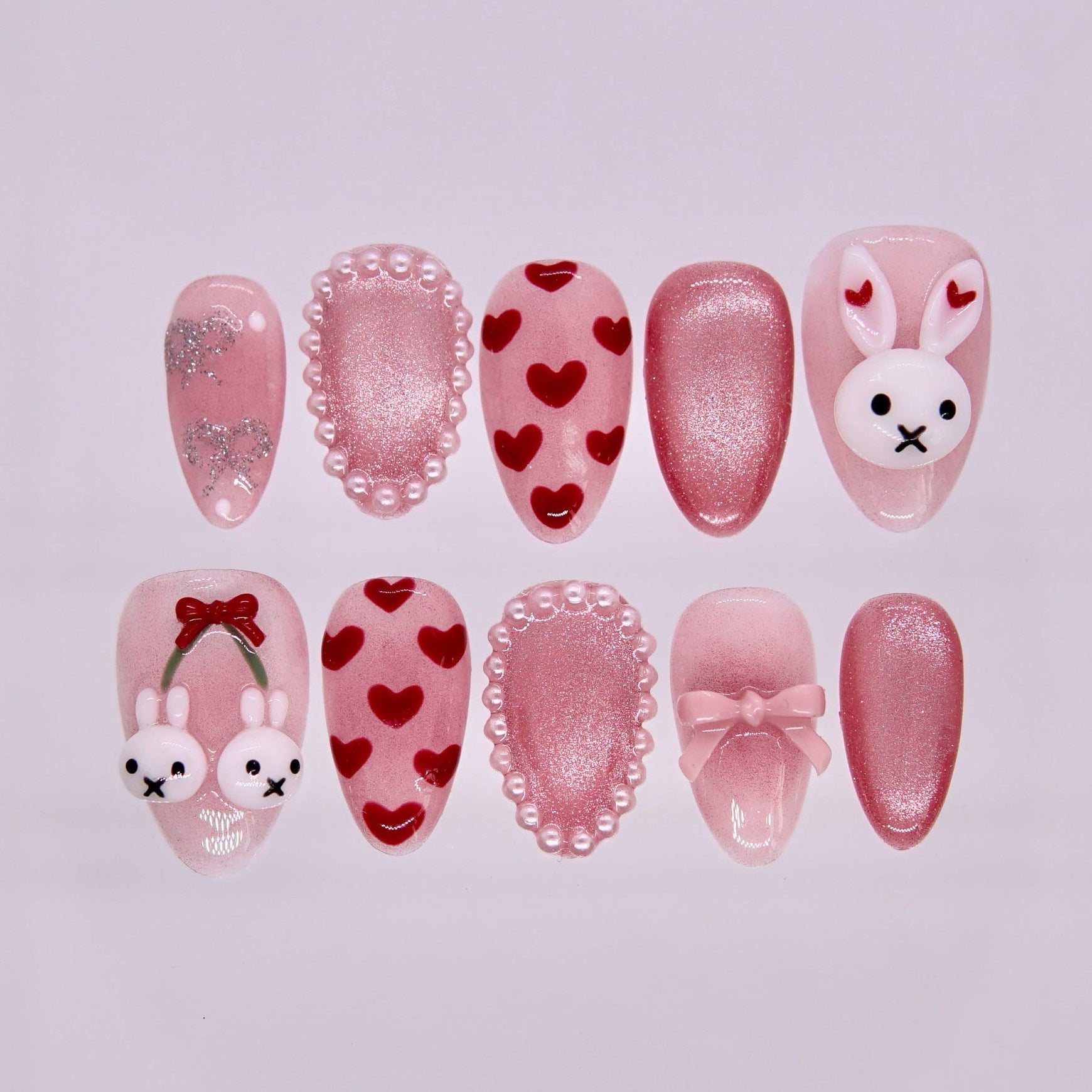 Rabbit zodiac press-on nails in blush pink with shimmer finish, heart patterns, pearl accents, bows, and bunny charms representing Lullaby and gentle self love.