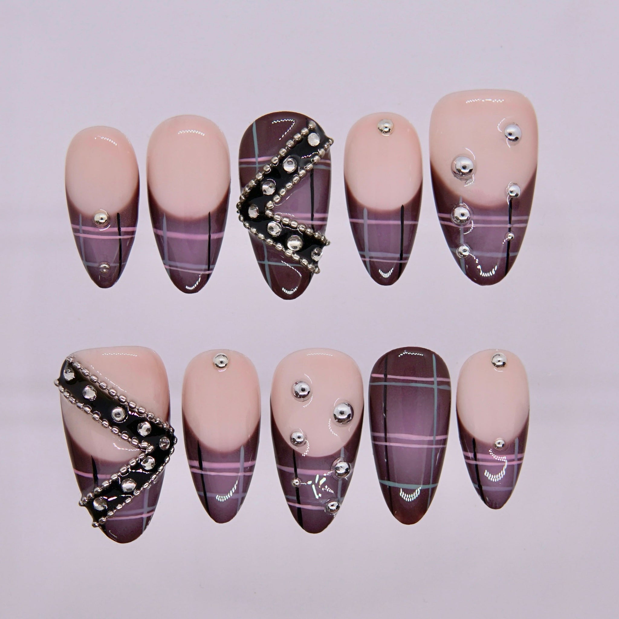 Mocha Rebel press-on nails featuring mauve plaid pattern with silver studs and blush French base.