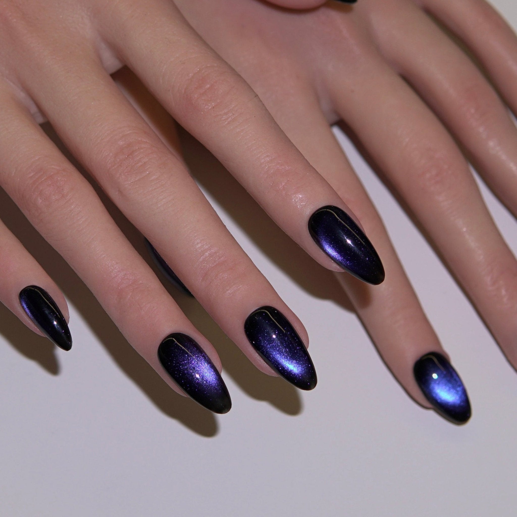 Close-up of deep blue cat-eye press-on nails glowing with moonlit reflection, inspired by ocean flow and calm intuition.