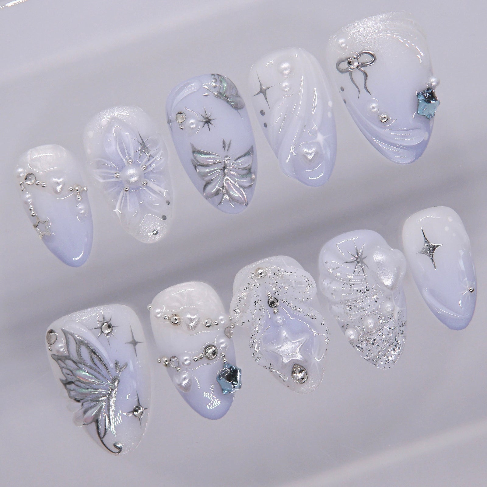 Close-up of silver butterfly wings and star trails on icy blue press-on nails.
