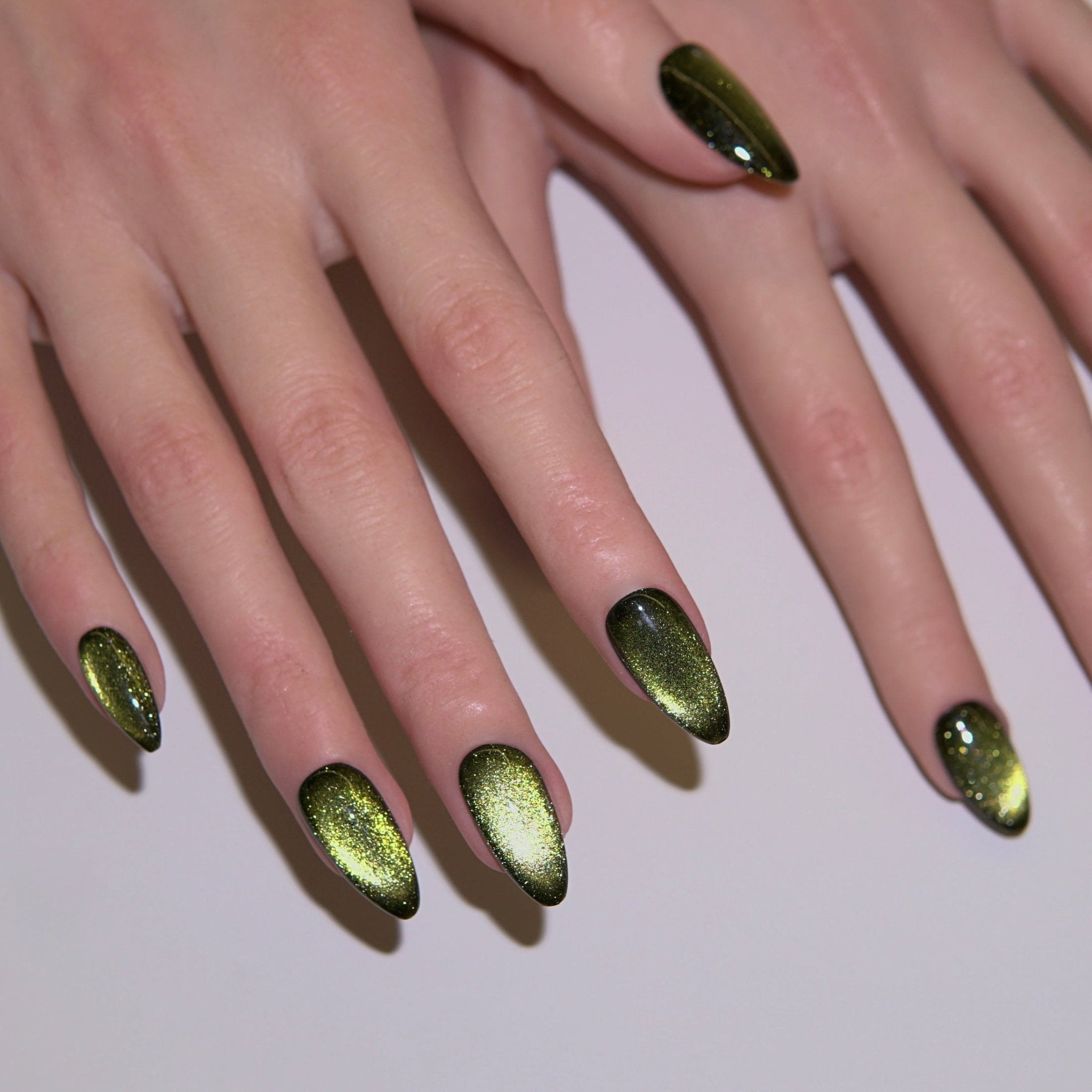 Close-up of black and gold cat-eye press-on nails glowing under soft light, representing grounding and calm energy.