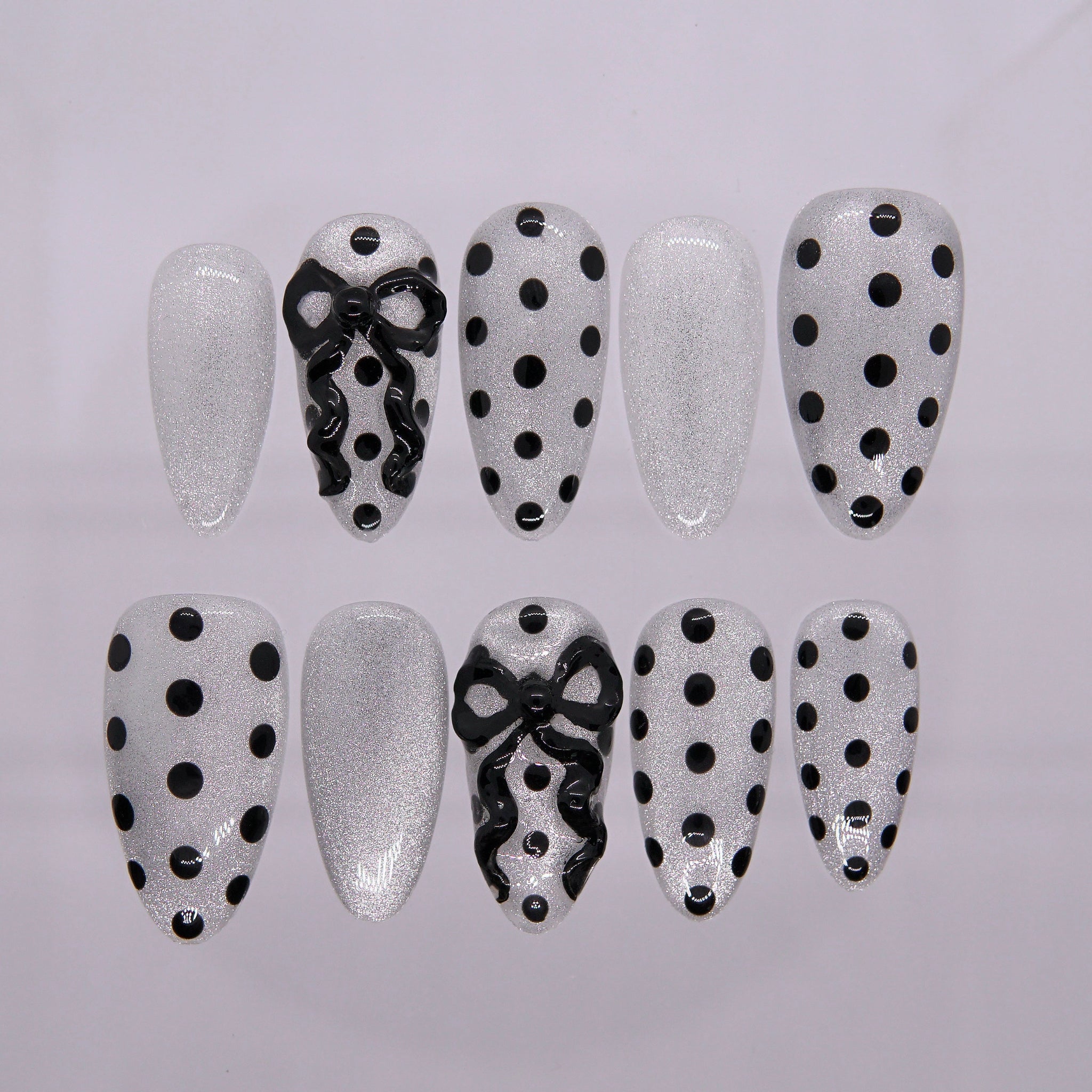 Black-and-white polka dot press-on nails with 3D bow accents.